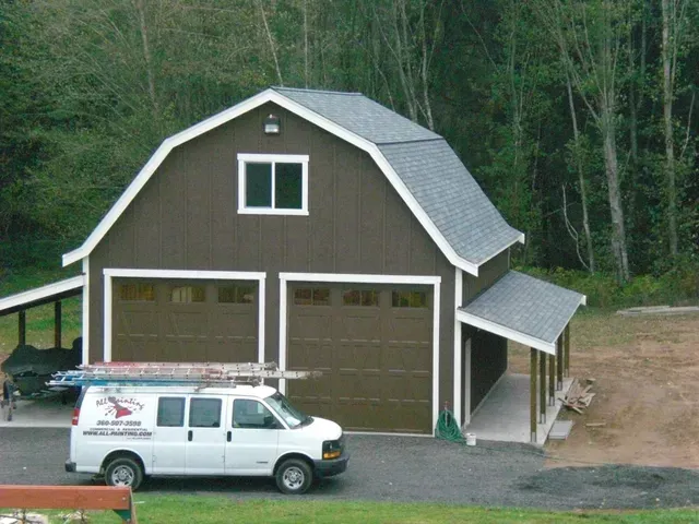 Brown garage with a white van parked in front, set beside a wooded area