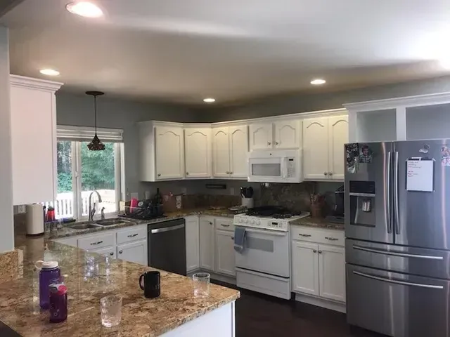 Bright modern kitchen with white cabinets, granite counters, and stainless steel appliances