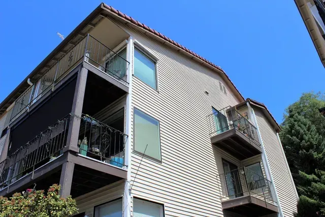Apartment building with balconies and green awnings against a blue sky