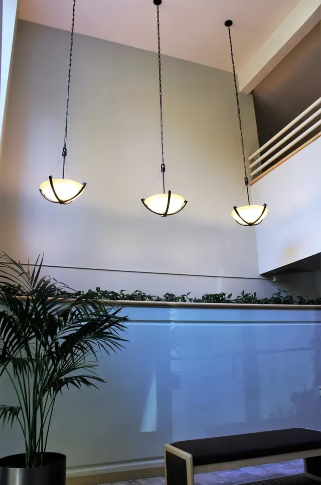 Modern lobby with three hanging pendant lights, a potted plant, and a bench