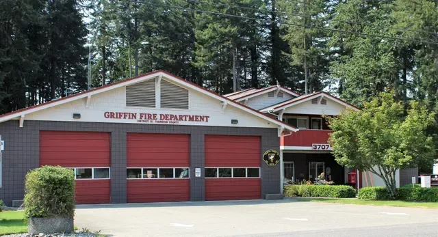 Exterior of Gresham Fire Department with red garage doors and trees in front