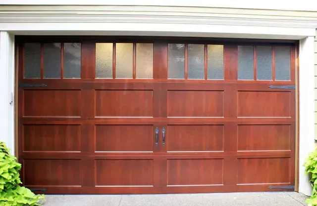 Wooden garage door with small upper windows, set in a light-colored house exterior