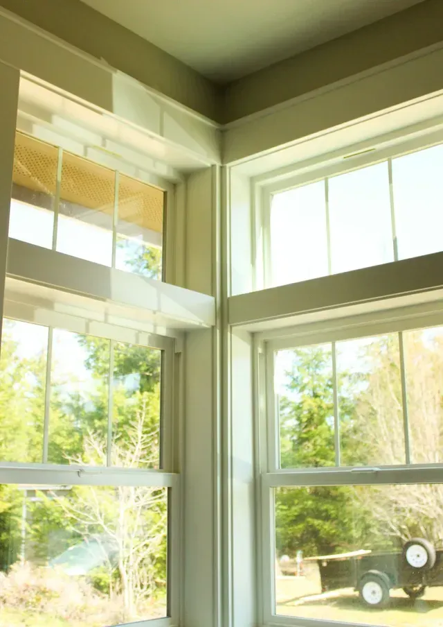 Bright room with large windows overlooking a green yard and a trailer outside.