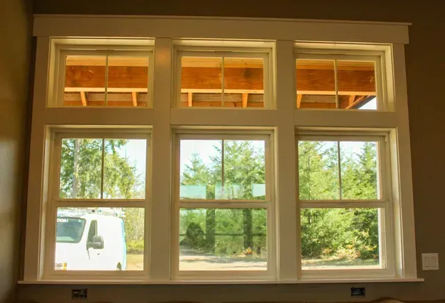 Large living room window with white trim, showing trees and a white truck outside