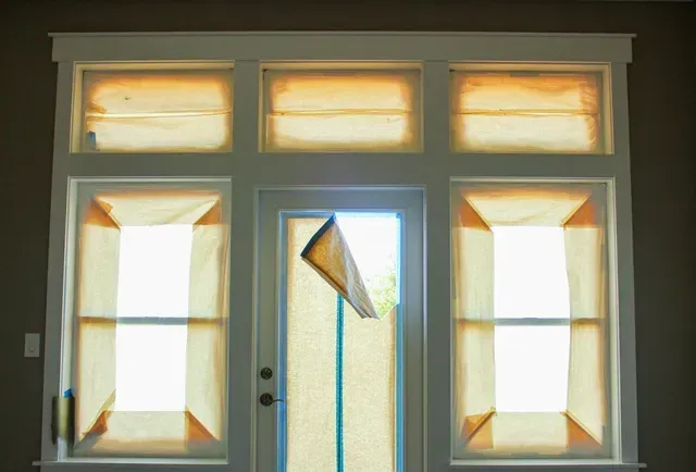 Front door with sidelights and transom windows, showing a broken pane hanging in the center.