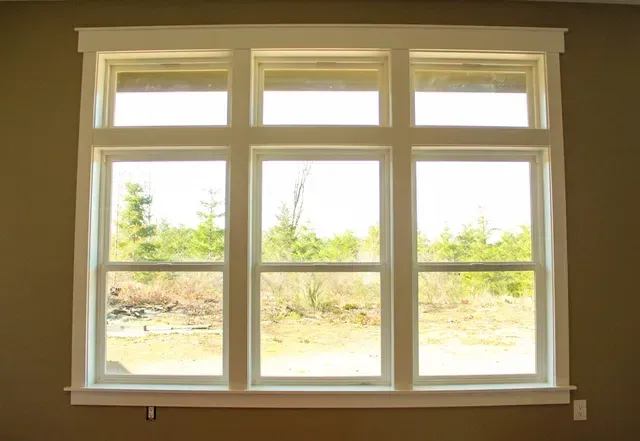 White-framed window with multiple panes looking out onto trees and a bright outdoor view