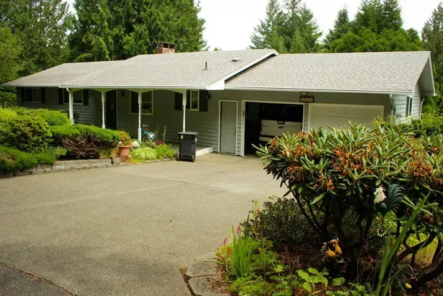 Single-story house with driveway, garage, and lush green landscaping