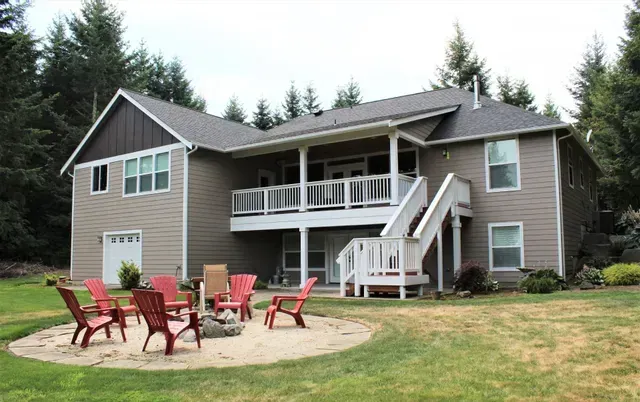 Backyard patio with red chairs and a two-story house with a balcony and stairs