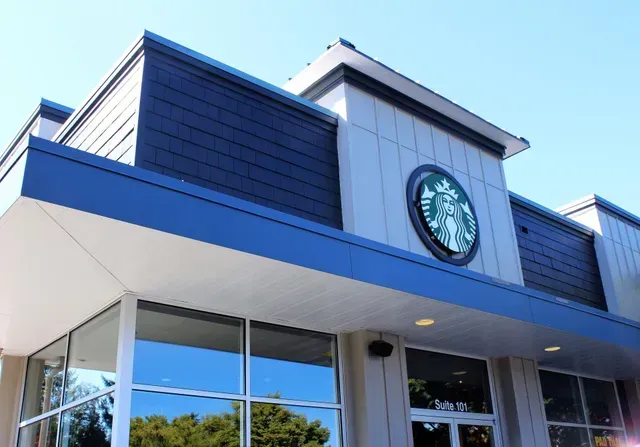 Starbucks storefront with blue trim and large windows under a bright sky