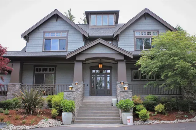 Gray two-story house with front porch, stairs, and landscaped yard