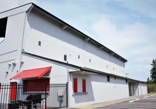 White building with red awnings and a black fence under a blue sky