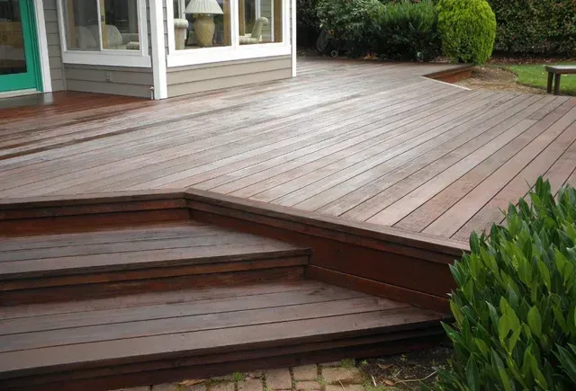 Wooden backyard deck with steps beside a house and patio doors