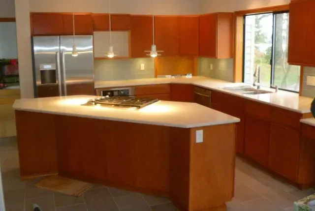 Modern kitchen with wood cabinets, stainless steel appliances, and large center island under bright windows