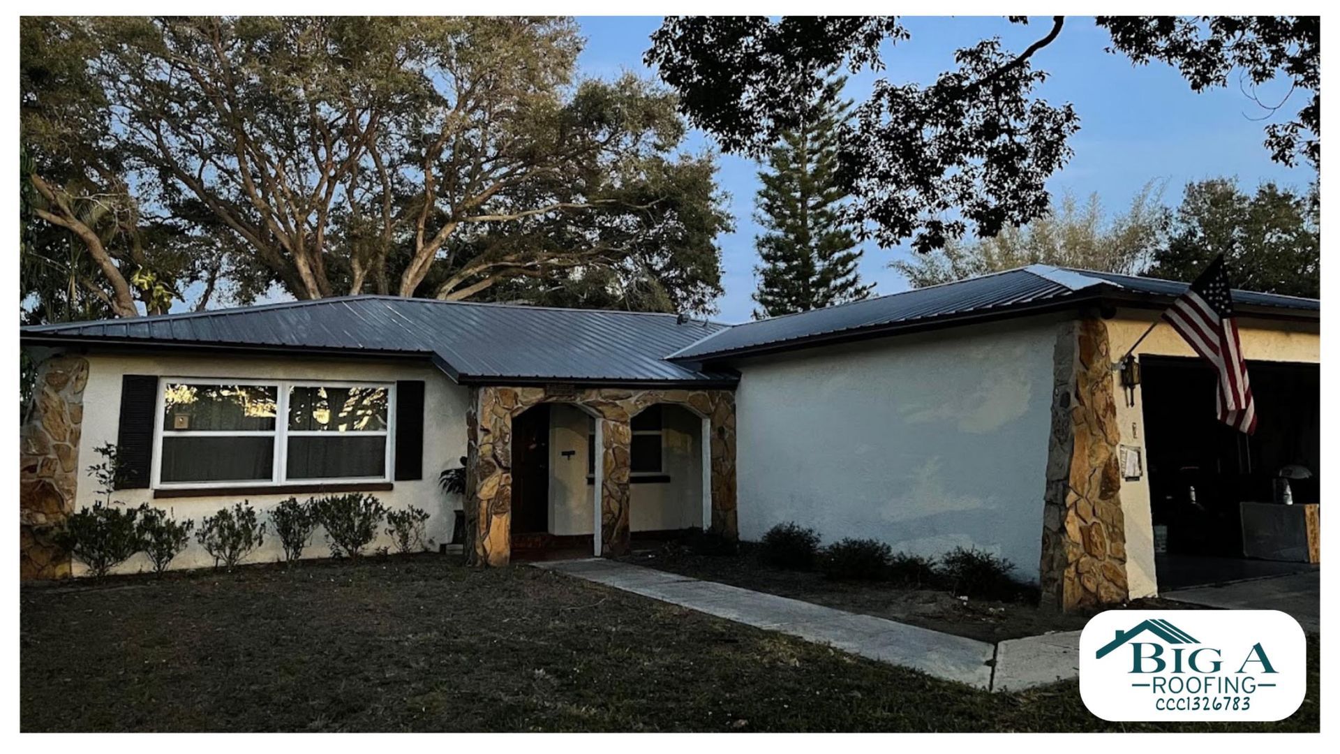 A single-story home with a metal roof, stone accents on the exterior, a front walkway, and a small company logo in the corner.