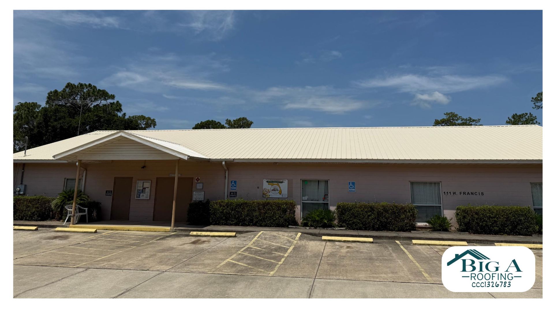 Single-story building with a light-colored metal roof, tan exterior, and a parking lot, featuring a Big A Roofing logo.