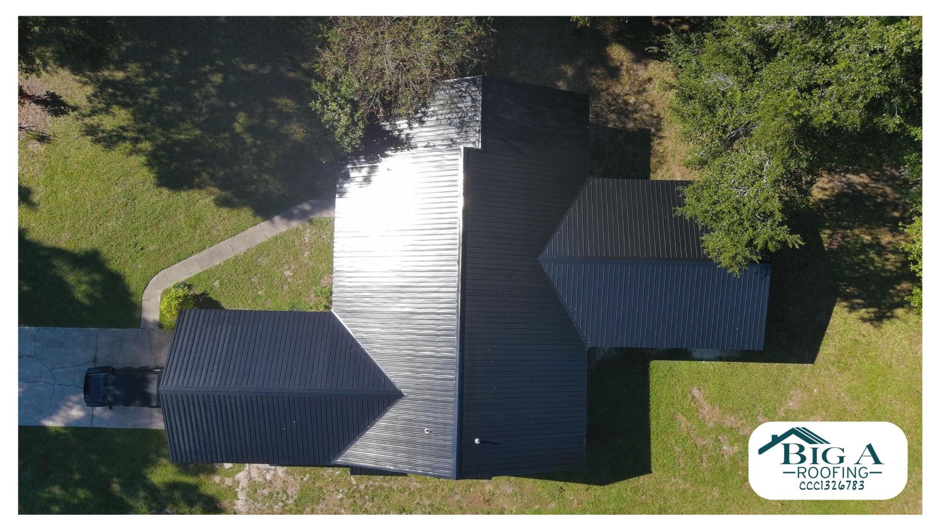 An aerial view of a house roof featuring a mix of new black shingle roofing and an unfinished silver metal section.