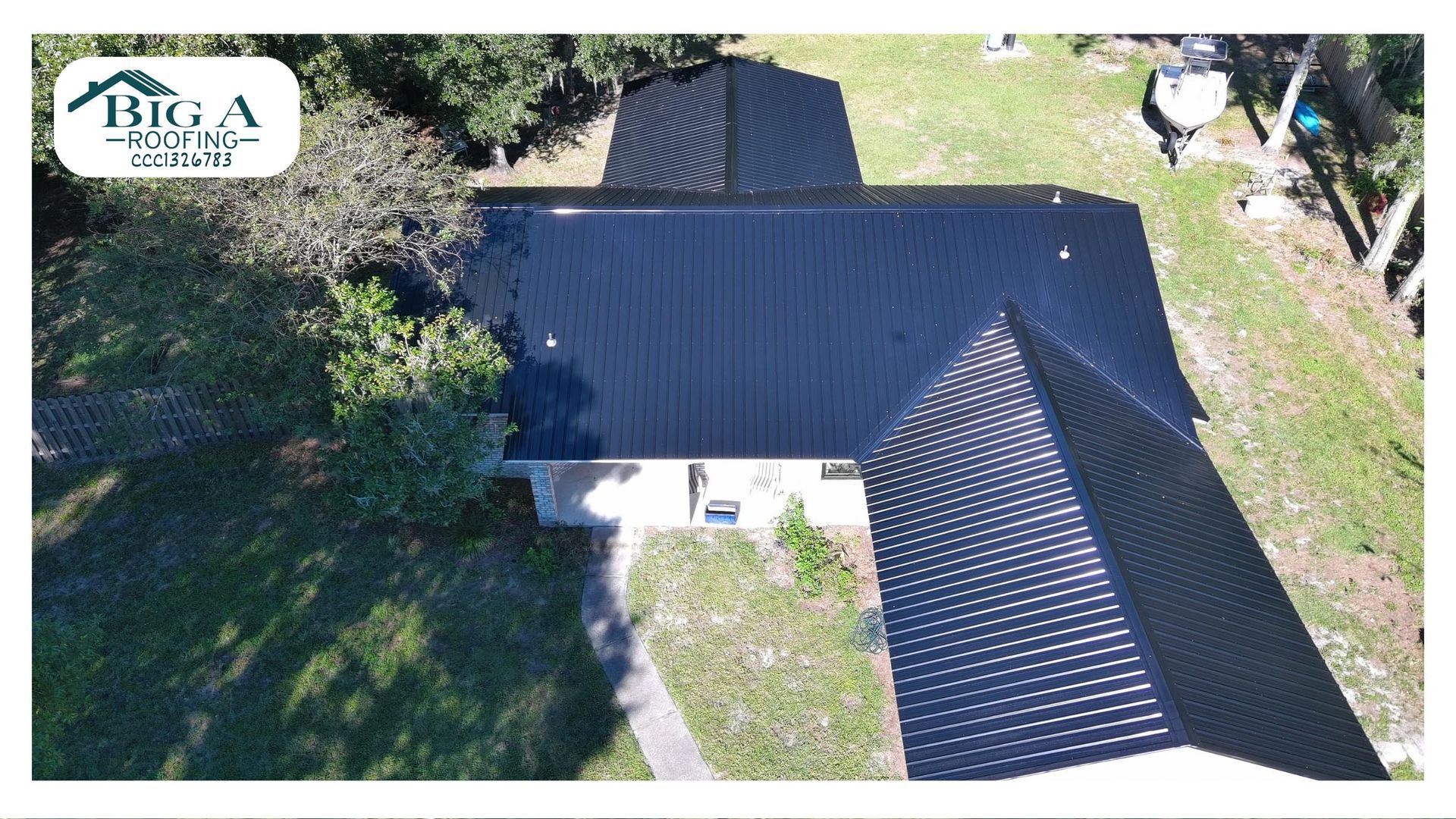 Aerial view of a residential house with a newly installed black metal roof, featuring a Big A Roofing company logo.