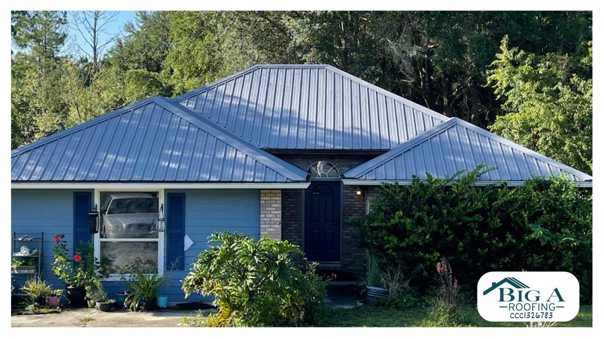 A blue house with a gray metal roof and a small garden, featuring a company logo for Big A Roofing in the corner.