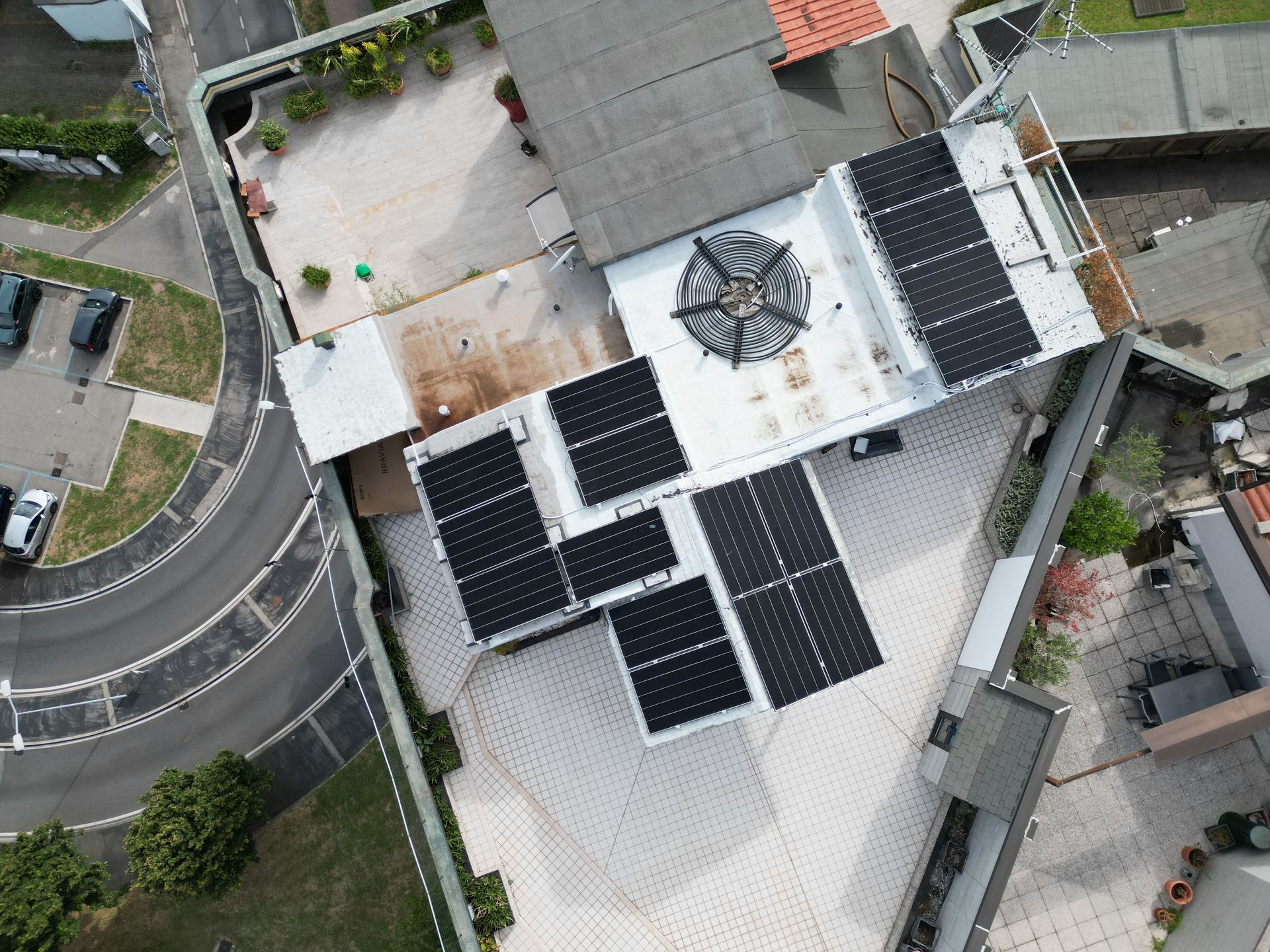 Vista aerea del tetto di un edificio con pannelli solari e una struttura a cupola centrale. Nelle vicinanze è visibile una strada curva.