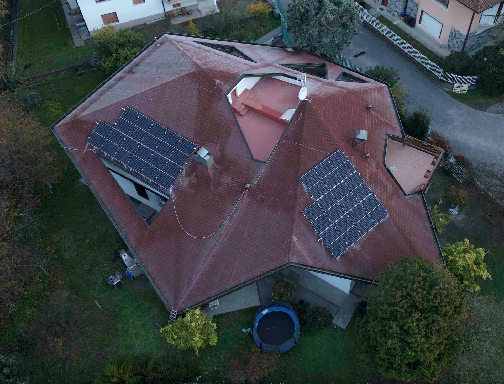 Vista dall'alto di una casa con un tetto rosso sfaccettato. Sul tetto sono installati pannelli solari.