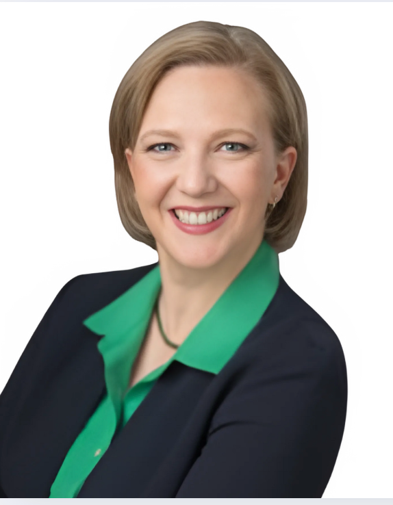 Woman in navy blazer and green shirt, smiling, looking at camera.