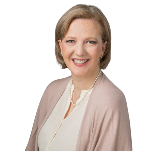 A woman wearing a pearl necklace and a pink cardigan smiles for the camera.