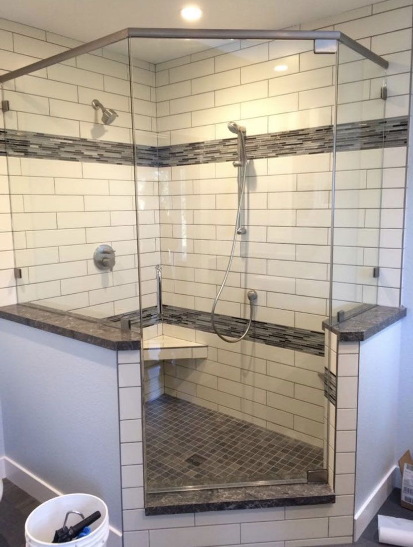 A bathroom with a walk in shower with a glass door.