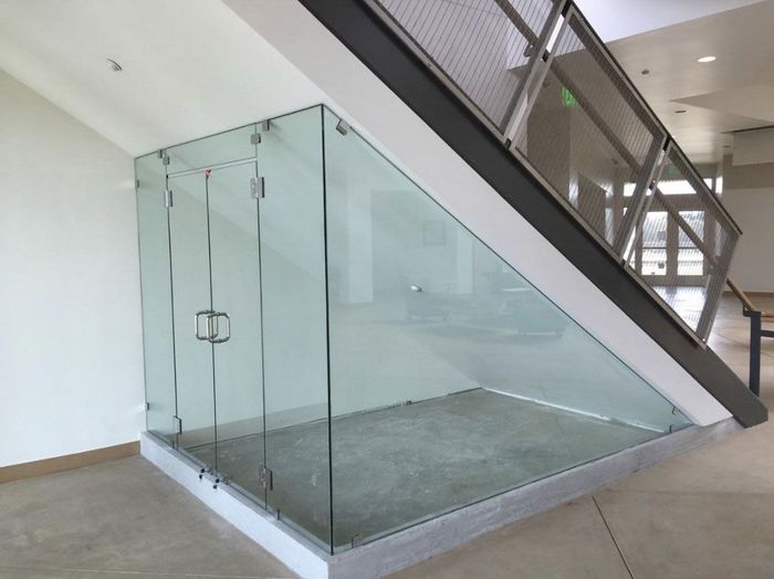 An empty room under a staircase with a glass wall