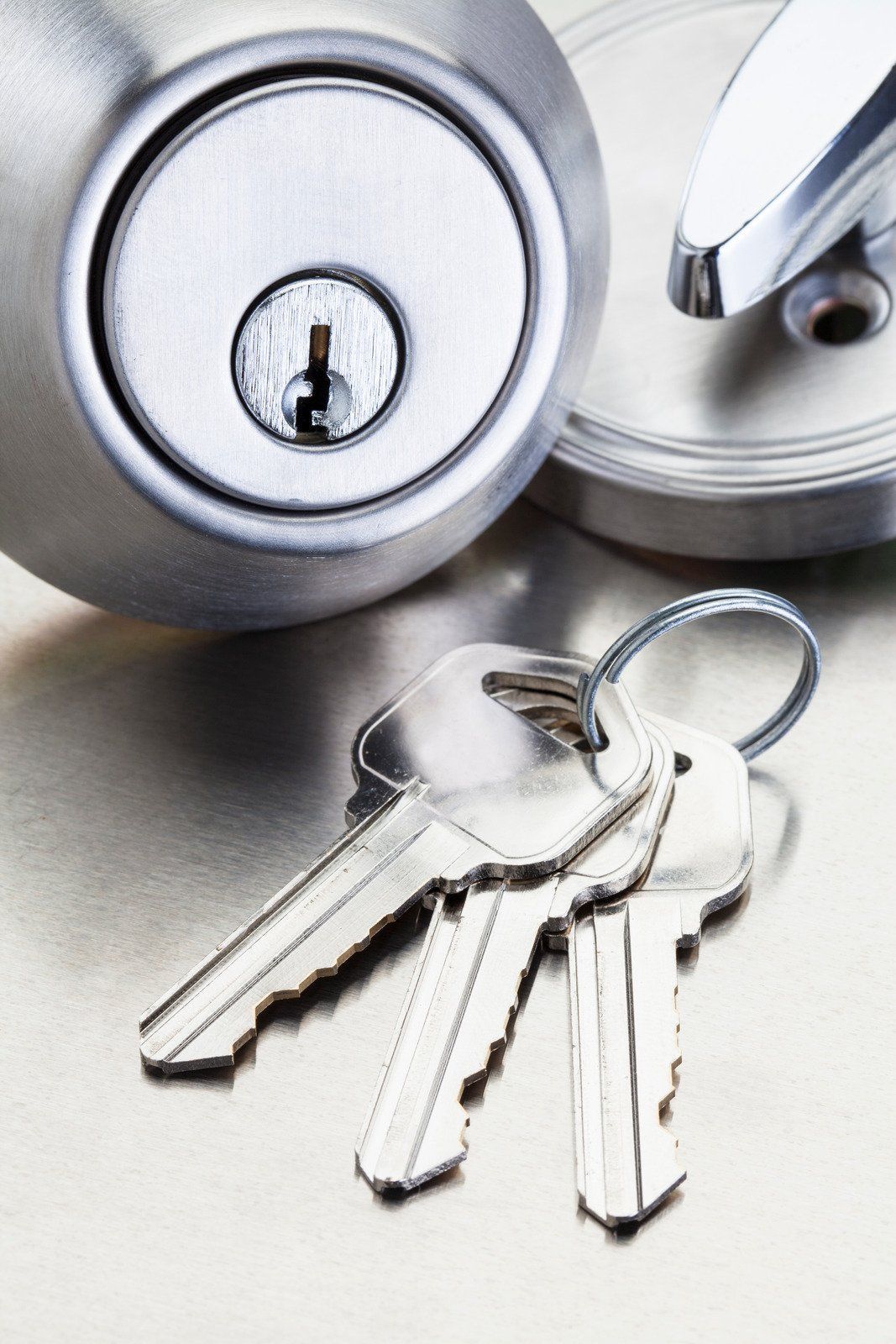 A bunch of keys are sitting next to a lock on a table