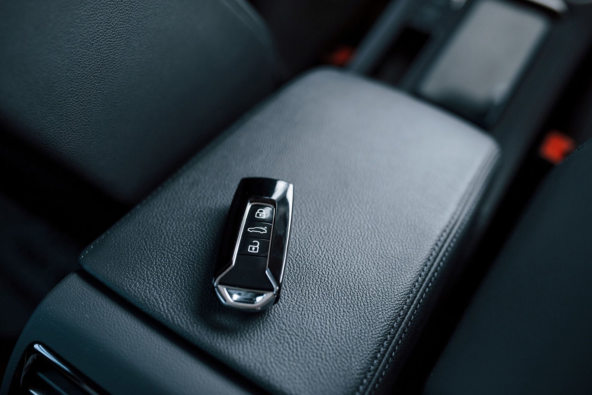 A car key is sitting on the arm rest of a car
