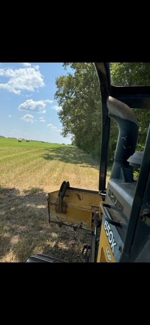 View from inside a machine cutting through a field of hay on a sunny day.