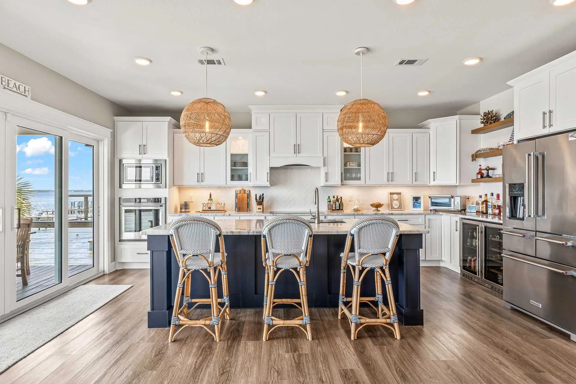 A kitchen with white cabinets , stainless steel appliances , a large island and stools.