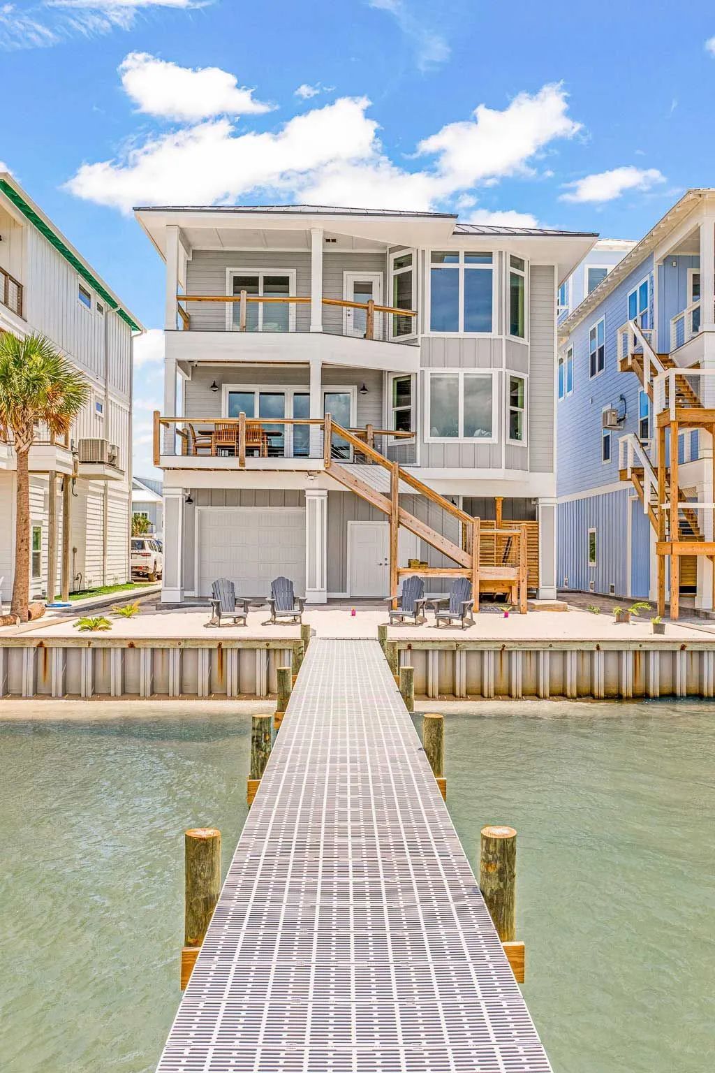 A large white house with a dock leading to it.