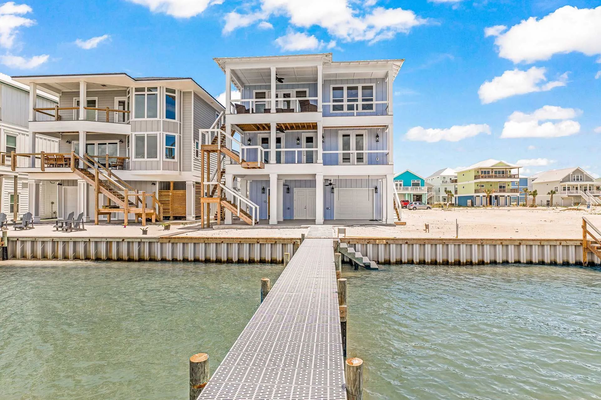 A large house is sitting on top of a body of water next to a dock.