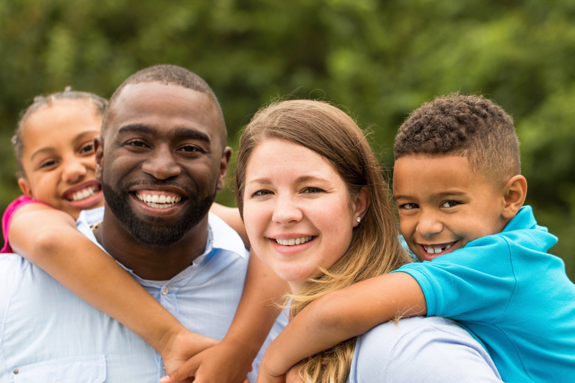 A family of four is posing for a picture in a park.