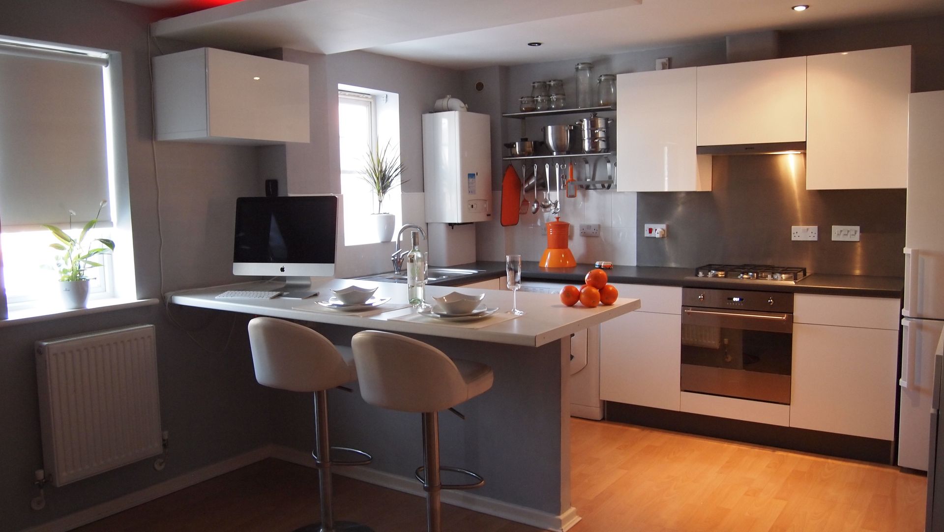 Modern kitchen with island, white cabinets, stainless appliances, and bar stools