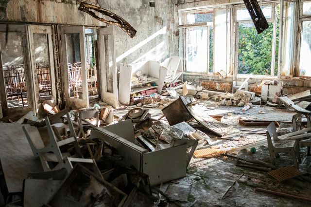 A room in an abandoned building with a lot of junk on the floor.