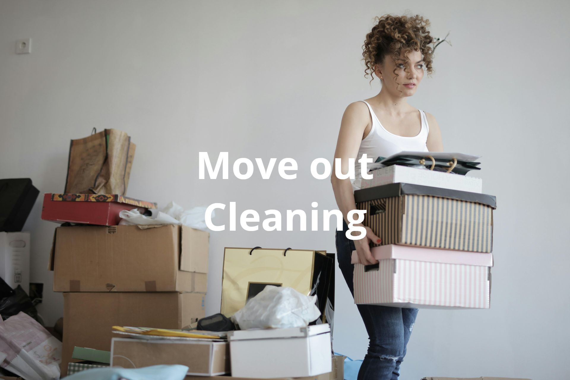 A woman is carrying a pile of boxes in a room.