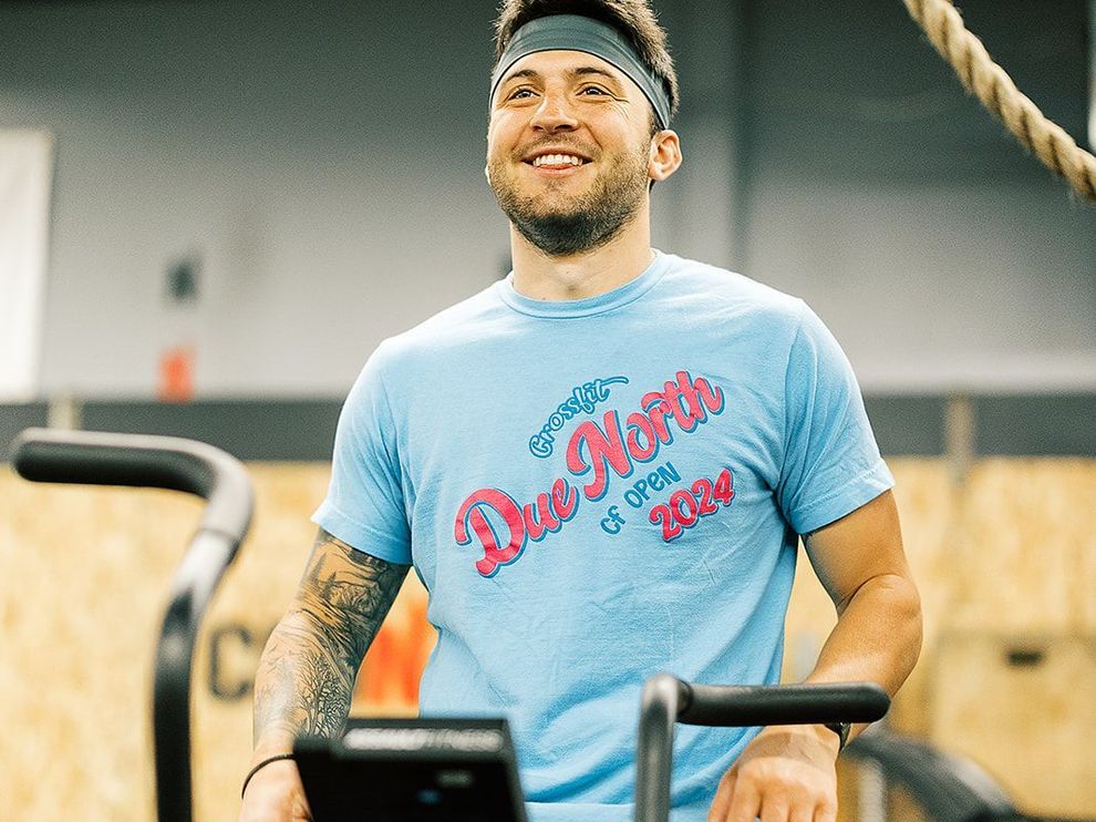 A man in a blue shirt is riding an exercise bike in a gym.