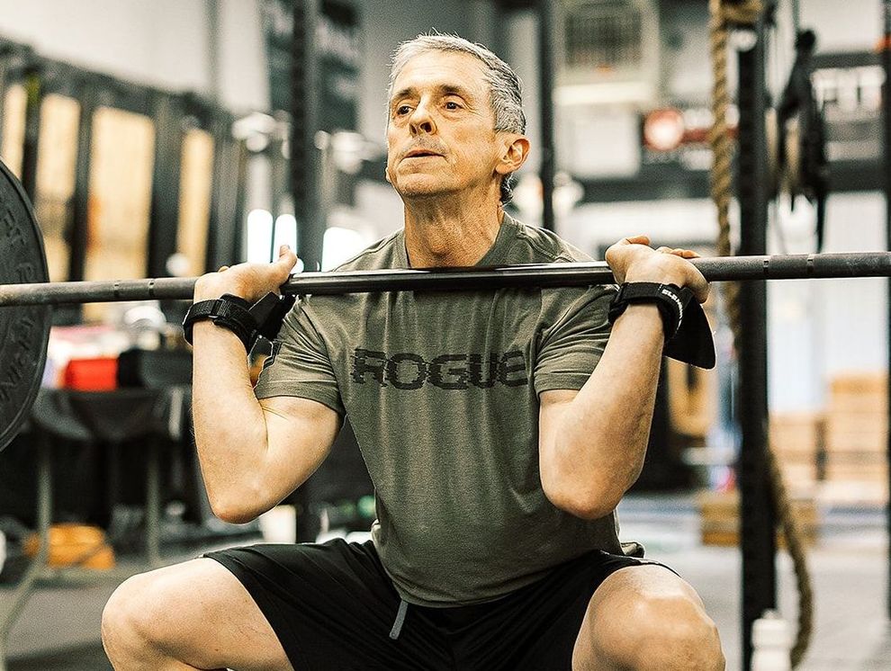 A man is squatting with a barbell in a gym.