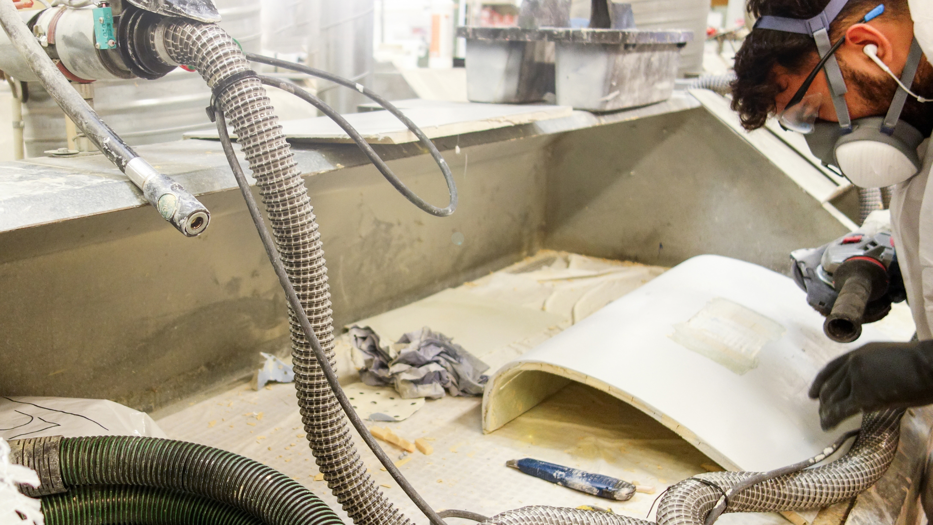 A man wearing a gas mask is working on a piece of concrete.