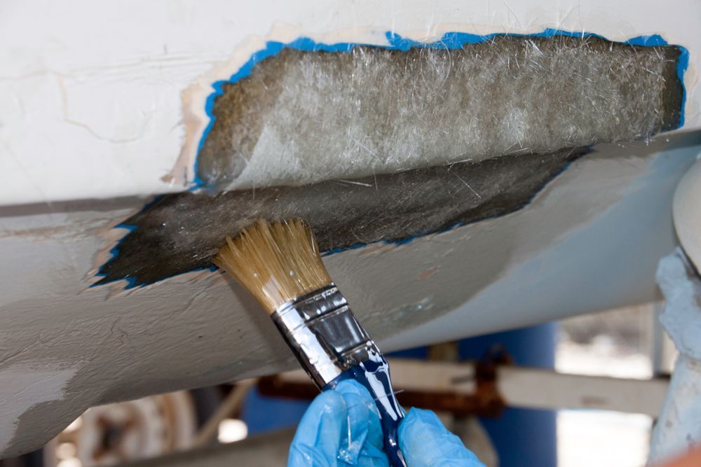A person is painting a boat with a brush.