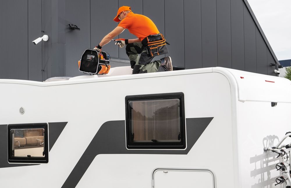 A man is working on the roof of a camper.