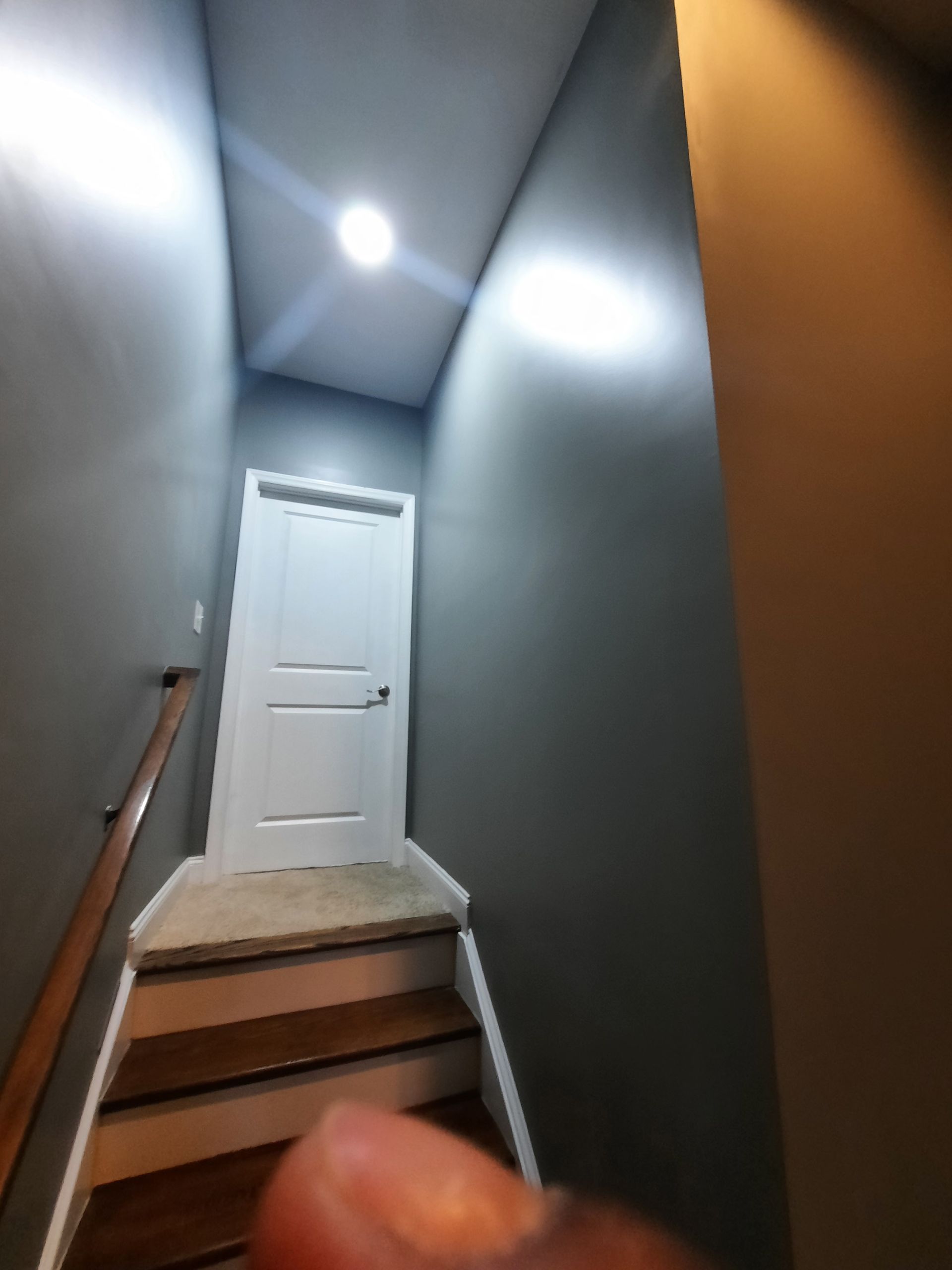 A person 's finger is pointing at a staircase leading to a door