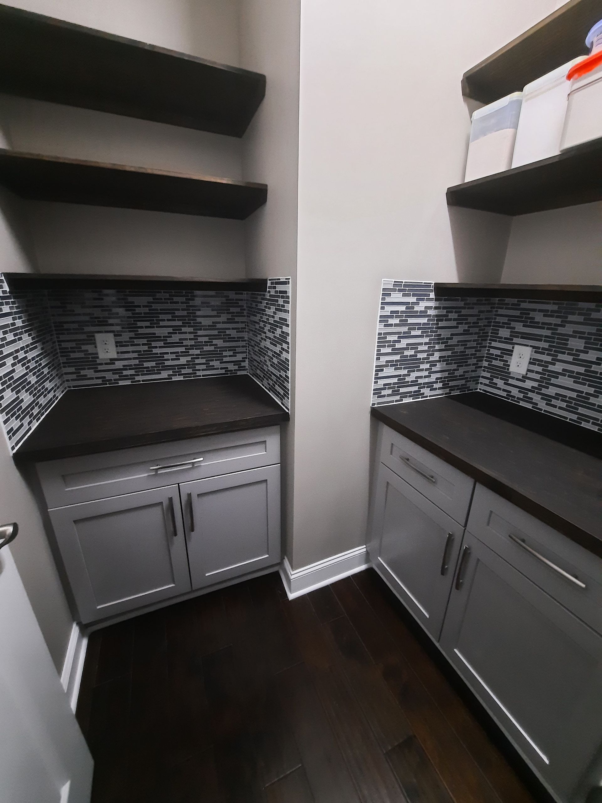 A kitchen with white cabinets and wooden shelves