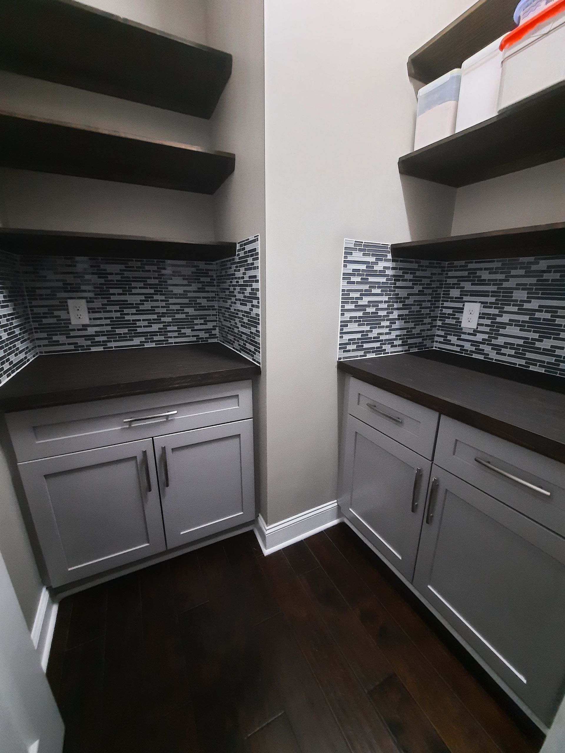 A pantry with gray cabinets and wooden shelves