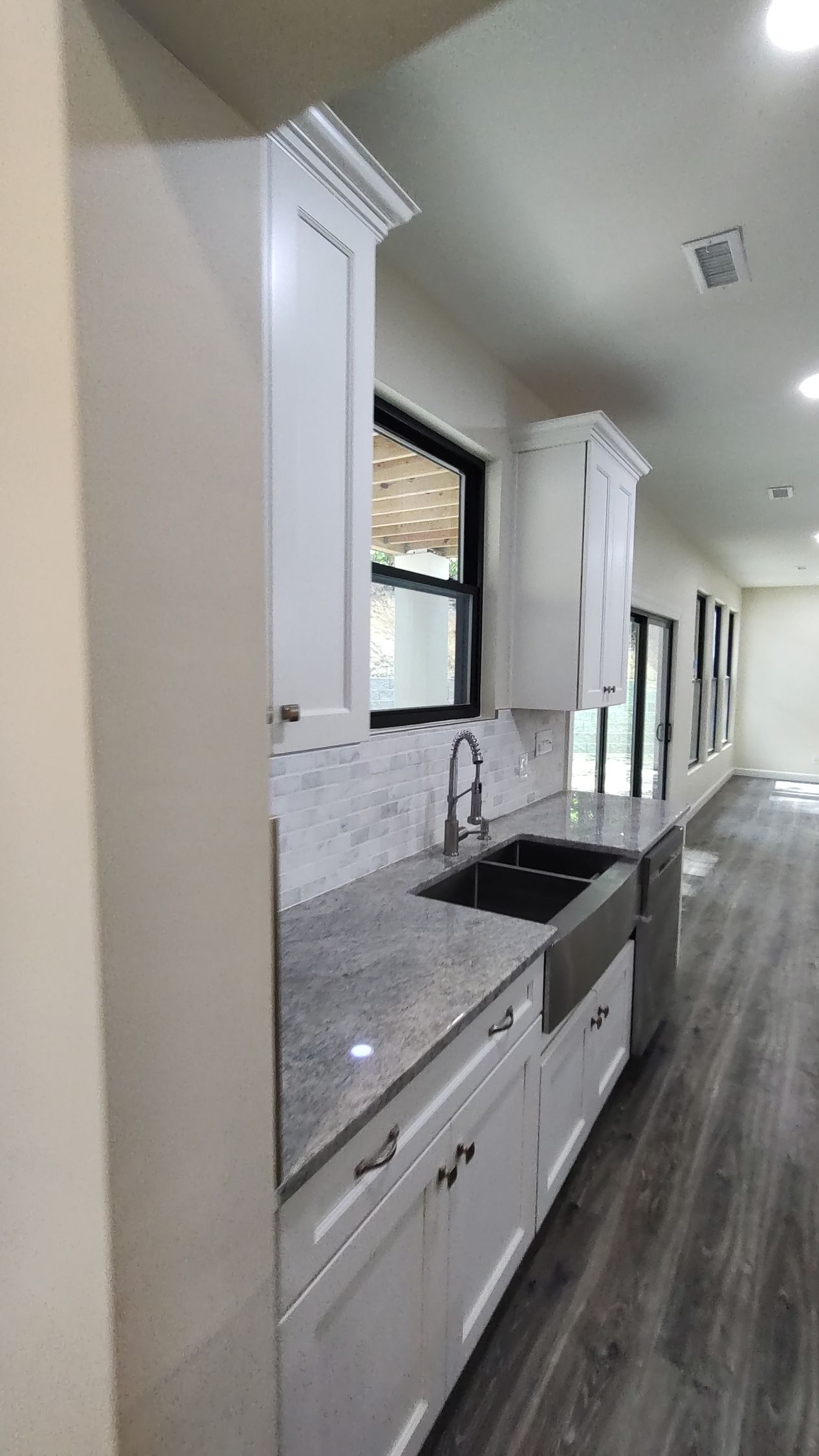 A kitchen with white cabinets , granite counter tops , and a sink.
