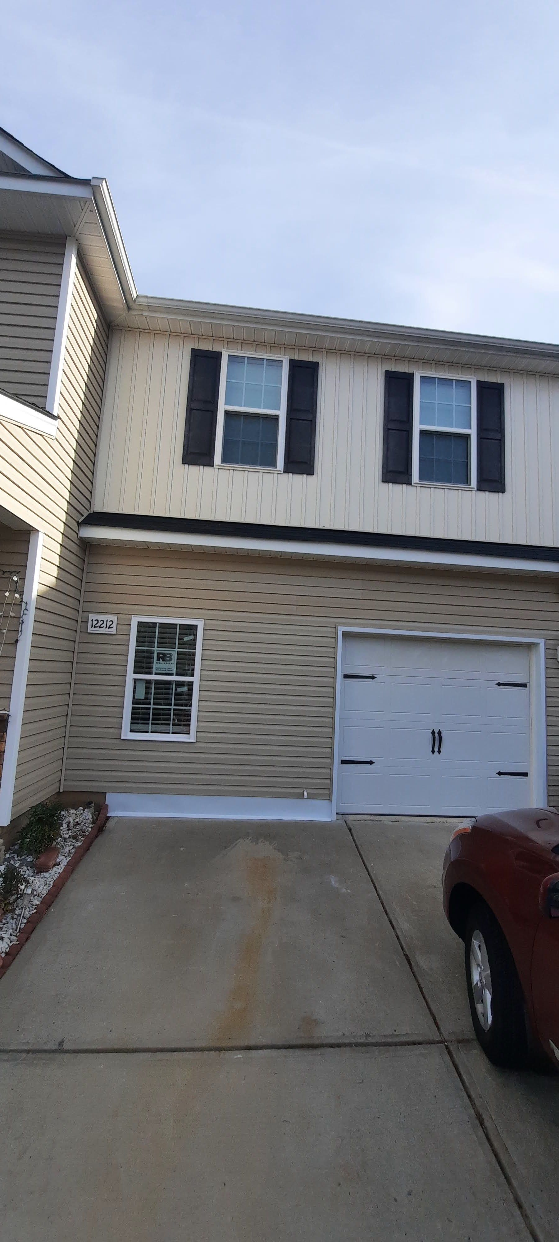 A car is parked in front of a house with a garage.
