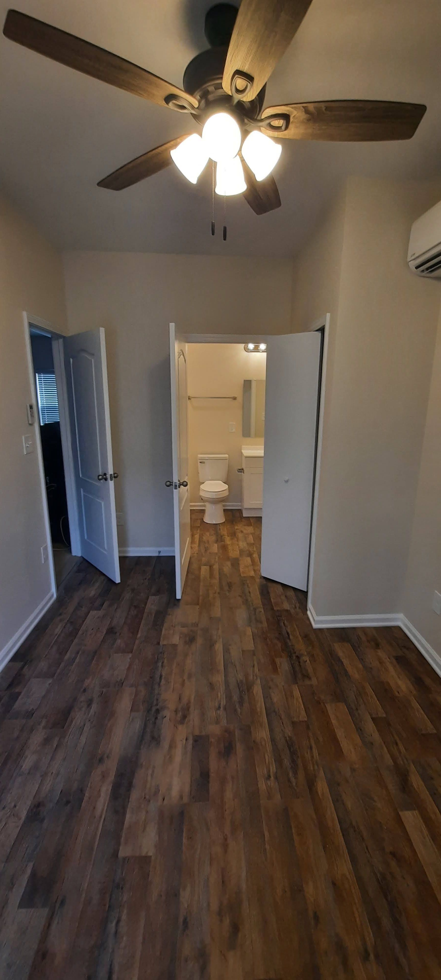 An empty room with hardwood floors and a ceiling fan.
