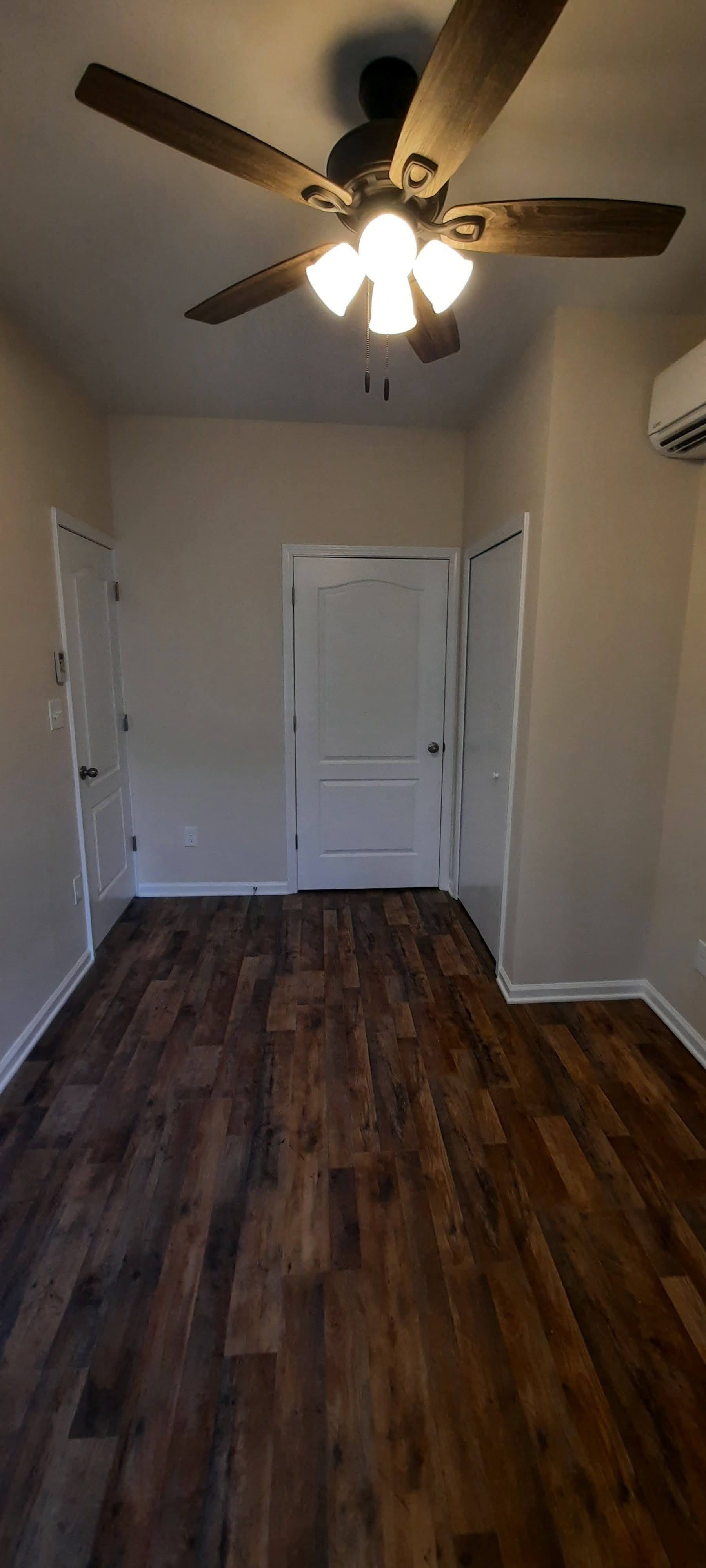 An empty room with hardwood floors and a ceiling fan.